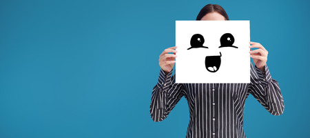 Smiling woman showing a big business card in front of her face against blue