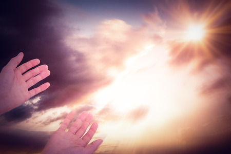 hands against blue and orange sky with cloudsの写真素材