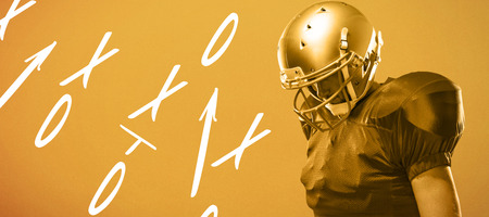 American football player looking down against orange backgroundの写真素材