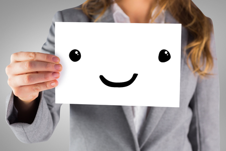 Businesswoman showing a card against grey vignetteの写真素材