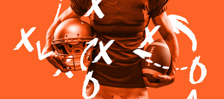 Midsection of American football player in red jersey holding helmet and ball against orangeの写真素材