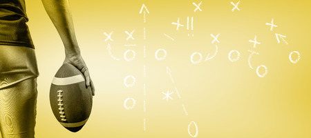 Cropped image of American football player holding ball against yellow vignetteの写真素材