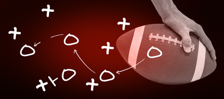 Close-up of American football player placing the ball against red background with vignetteの写真素材