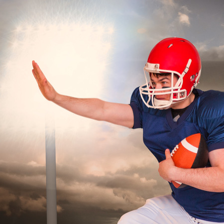 American football player jumping with the ball against spotlight in skyの写真素材