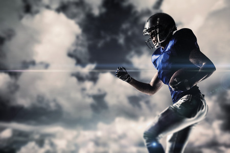 American football player running against blue sky with white cloudsの写真素材