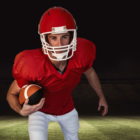 Rugby player with ball posing against football pitch at nightの写真素材