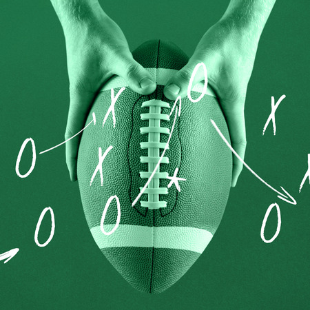 American football player holding up football against greenの写真素材