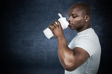 Fit man with protein shake against black backgroundの写真素材