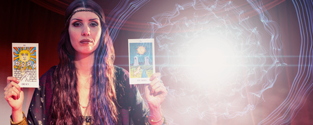 Portrait of fortune teller woman showing tarot cards  against background with shiny spiralの写真素材