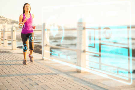 Fit woman jogging at promenade against fitness interfaceの写真素材