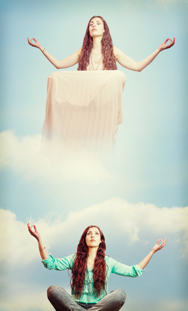 Woman meditating against blue sky with white cloudsの写真素材