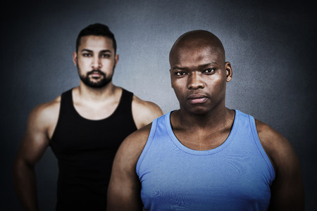 Strong friends looking at camera against black wallの写真素材