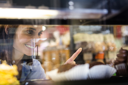 Pretty smiling woman choosing her dessert in supermarketの写真素材