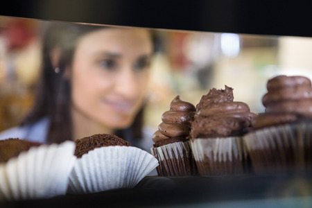 Pretty smiling woman choosing her dessert in supermarketの写真素材