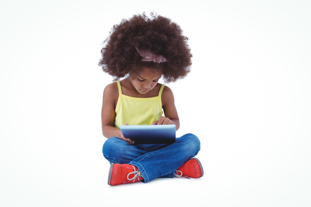 Cute girl sitting on the floor using tablet on white screenの写真素材