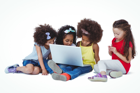 Cute girls sitting on the floor using laptop on white screenの写真素材
