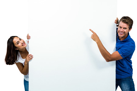Portrait of smiling man and woman behind board against white backgroundの写真素材