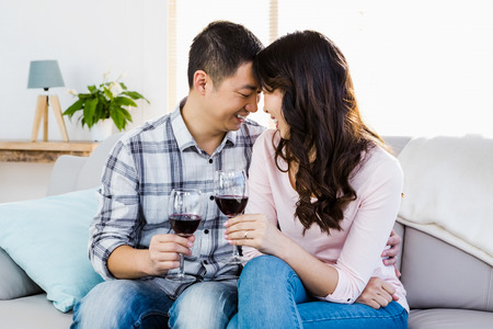 Happy couple drinking wine at homeの写真素材