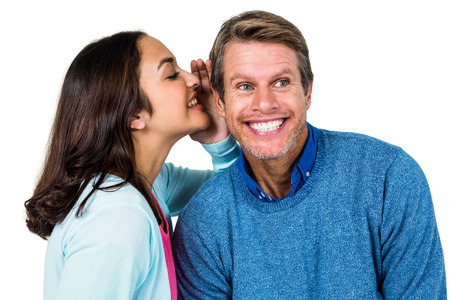 Woman sharing secret with man against white background