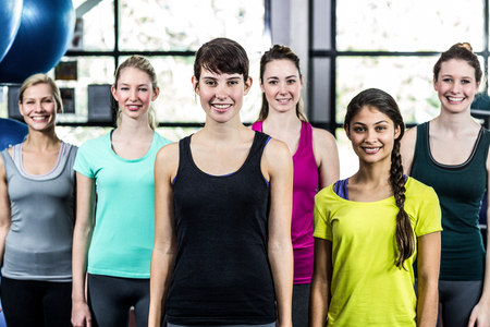 Fit smiling group standing straight in gymの写真素材