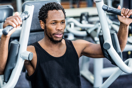 Fit man using exercise machine at the gym