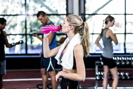 Blonde woman drinking water after working out in the gym