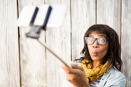 Casual smiling woman taking a selfie against wooden plankの写真素材