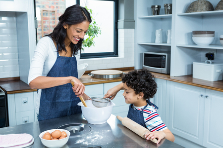 Smiling mother cooking with her son in kitchen at homeの写真素材