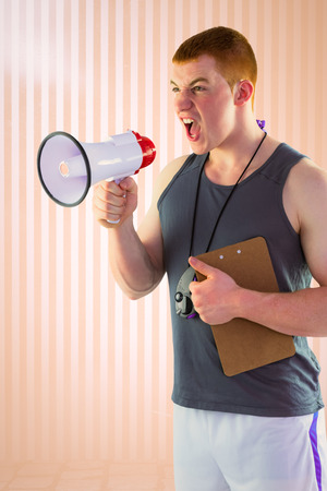 Angry personal trainer yelling through megaphone  against peach backgroundの写真素材