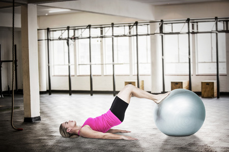 Side view of woman exercising with ball against interior view of a gymの写真素材