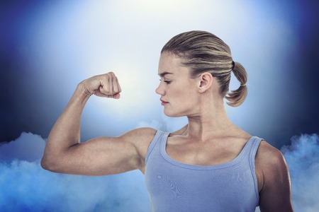 Muscular woman flexing her muscle against cloudy skyの写真素材