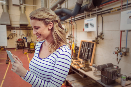 Pretty girl with phone against workshopの写真素材