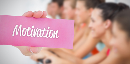 The word motivation and young woman holding blank card againstの写真素材