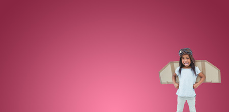 Standing girl with fake wings pretending to be pilot against red vignetteの写真素材