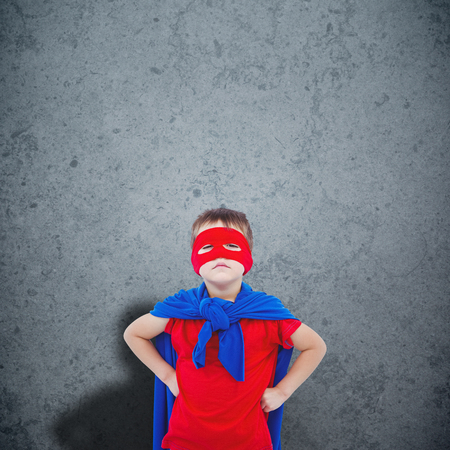 Masked boy pretending to be superhero against dirty old wall backgroundの写真素材