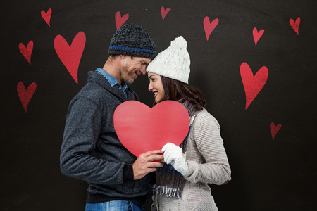 Festive couple in winter clothes against blackboardの写真素材