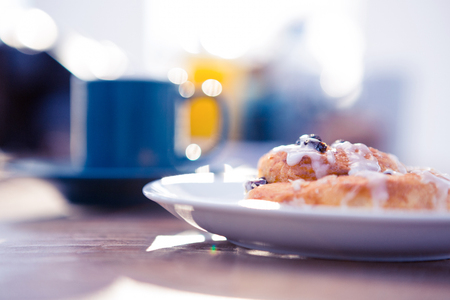 Sweet food served in plate by coffee cup on table at office