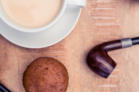 Close-up of coffee with muffin and smoking pipe on tableの写真素材