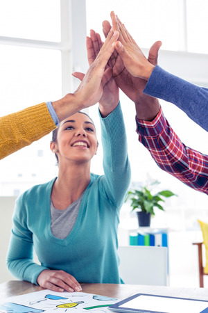 Cheerful Business woman doing high five with team in creative officeの写真素材