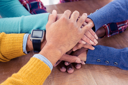 Business team with stacked hands on desk at creative office