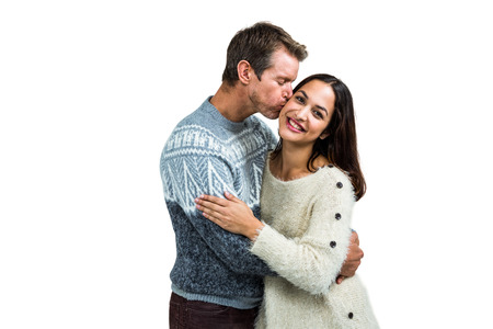Boyfriend kissing girlfriend while standing against white background