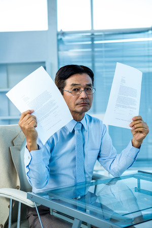 Busy businessman showing papers in officeの写真素材