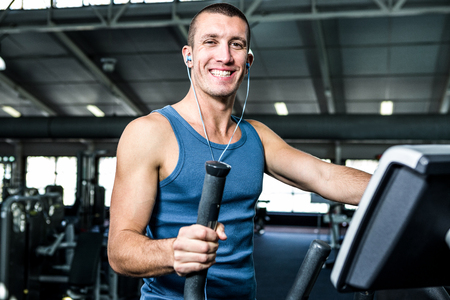 Smiling man working out with headphones on at the gym