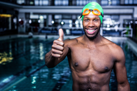 Fit swimmer standing with thumbs up in swimming poolの写真素材