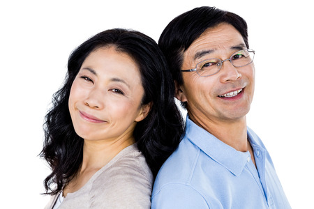 Couple with their backs to each other and smilingの写真素材