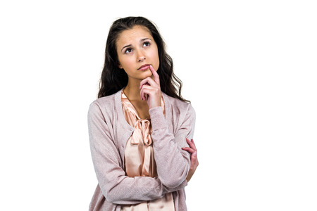 Thoughtful woman looking away with finger on mouth over white backgroundの写真素材