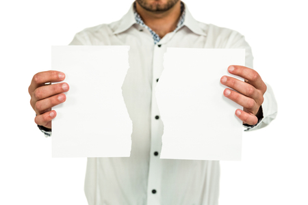 Standing man showing torn papers while standing on white backgroundの写真素材
