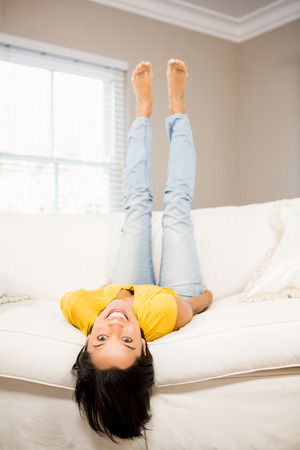Smiling brunette on sofa with legs up looking at the cameraの写真素材