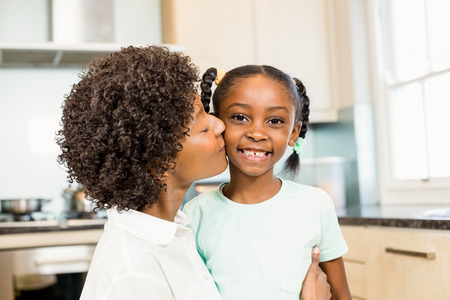 Mother kissing daughter in the kitchenの写真素材