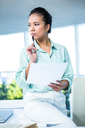 Smiling businesswoman sitting on her desk in officeの写真素材